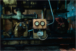 A rusty control panel and machinery in dim light, remnants of a forgotten era.