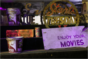 Old popcorn buckets and faded signs at a forgotten theater, memories lingering in the air.