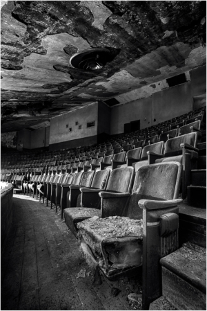Desolate theater seats stand in shadows, a ghost of past performances.