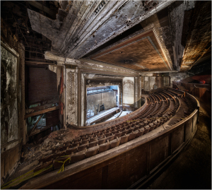 Interior view of an abandoned theater with decaying architecture and empty seating.