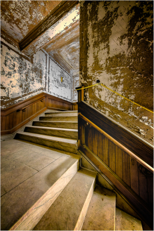 A dimly lit staircase veiled in peeling paint and shadows