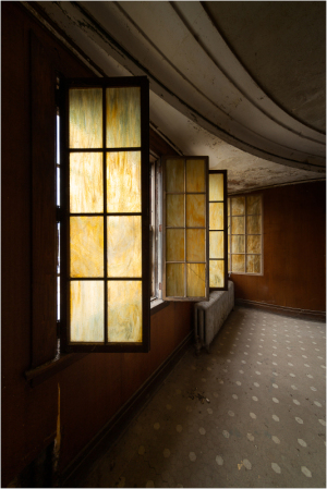 A dimly lit room with stained glass windows casting eerie hues.