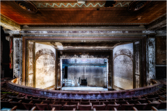 Abandoned theater interior with faded grandeur and empty stage.