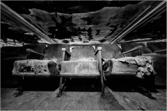 Decayed theater seats amidst shadowy desolation and ruin, whispering tales of yore.