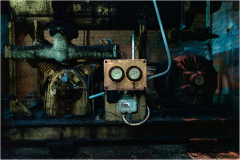 A rusty control panel and machinery in dim light, remnants of a forgotten era.