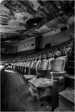 Desolate theater seats stand in shadows, a ghost of past performances.
