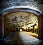 An abandoned theater with a curved ceiling and wooden walls, creating a moody atmosphere.