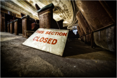 Sign saying 'THIS SECTION CLOSED' near old theater seats, adding to the eerie vibe.
