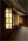 A dimly lit room with stained glass windows casting eerie hues.