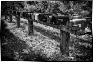 Row of mailboxes on a wooden post in black and white