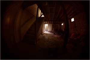 Dimly lit basement with stairs and an open door at the far end