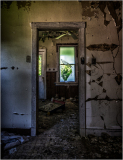 View through a doorway into a dilapidated room with peeling walls.