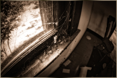 Dusty window with cobwebs and debris in an abandoned room